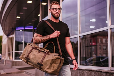 Junger Mann mit einer Reisetasche aus Leder